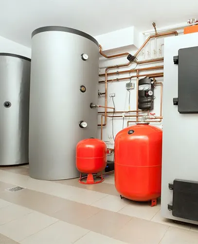 Boiler system with tanks, pipes, and pressure vessels in a utility room.