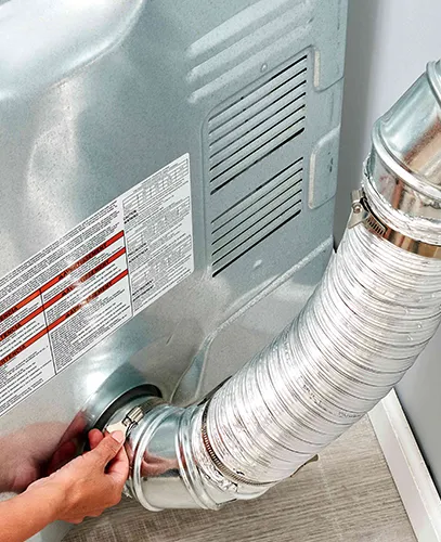 Dryer duct installation showing the vent being attached to the back of a dryer.