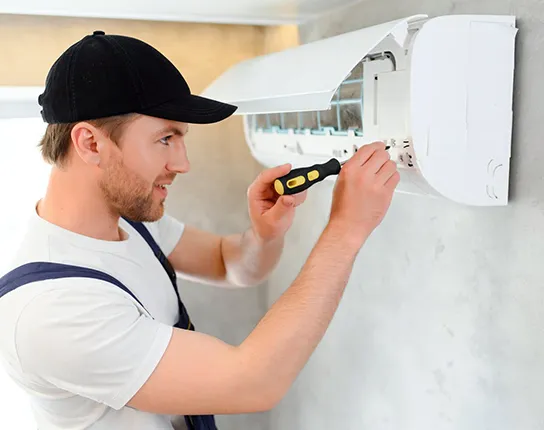 Technician repairing residential air conditioning with a screwdriver.