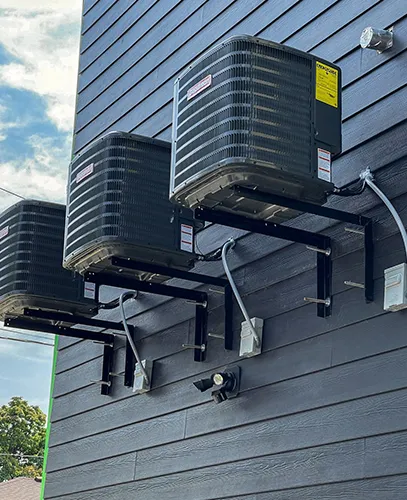 Three air conditioning units mounted on a building exterior.